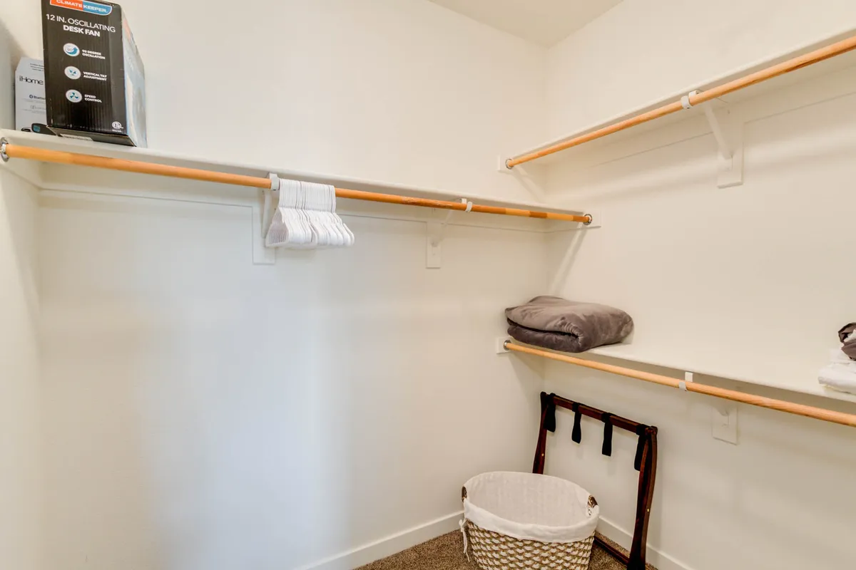 An organized closet with shelves, baskets, and neatly folded towels conveys ample storage and a sense of order. The minimalistic, functional design offers a glimpse of the generous walk-in closet described in the suite.